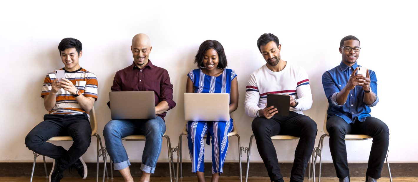 Colleagues sitting in a row using digital devices